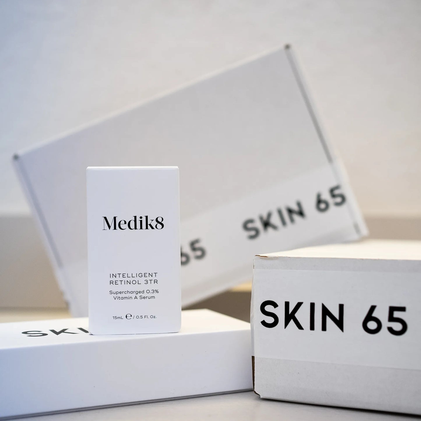 Medik8 Intelligent Retinol 3TR 15ml In the Box with Skin 65 Branding in he Background
