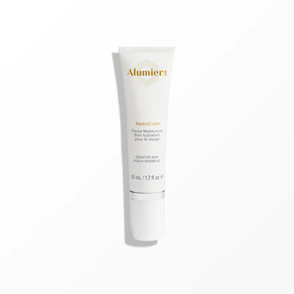 A cylindrical bottle of AlumierMD HydraCalm Facial Moisturizer stands upright on a white surface. Text on the bottle includes "SENSITIVE SKIN PEAUX SENSIBLES" and the volume "50 mL / 1.7 fl oz."