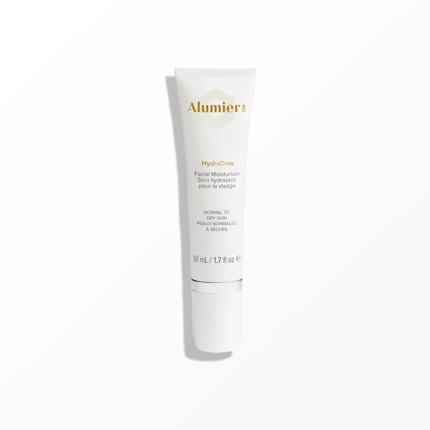 A white cylindrical bottle with a silver cap labeled "Alumier HydraDew Facial Moisturizer for normal to dry skin, 50 mL / 1.7 fl oz," stands upright on a white surface against a pale background.