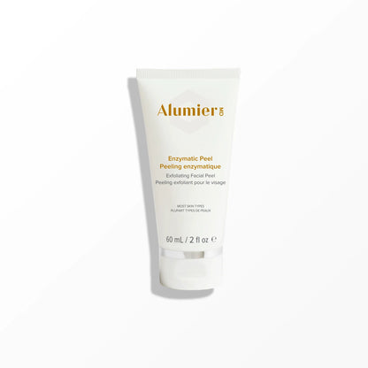 A white squeeze tube labeled "AlumierMD" and "Enzymatic Peel Exfoliating Facial Peel" stands upright on a smooth surface. Additional text reads, "All Skin Types / Tous Types De Peaux," "90 mL / 3 fl. oz e."