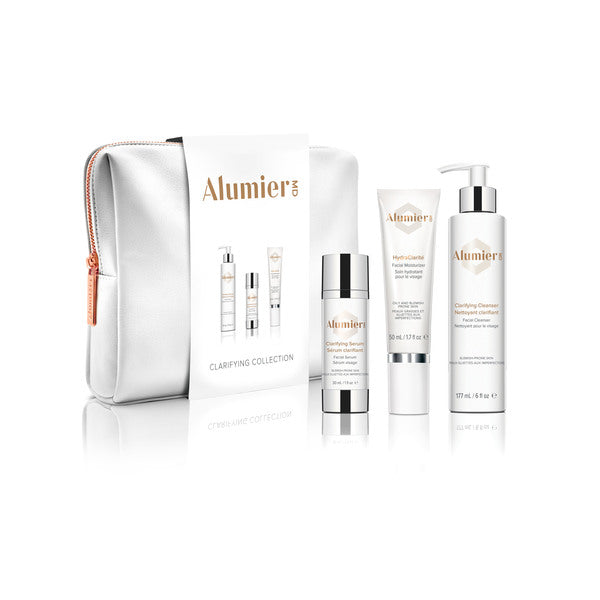 AlumierMD Clarifying Collection includes a silver zippered bag, Clarifying Serum, HydraClarite Moisturizer, and Clarifying Cleanser in lotion and pump bottle forms. The products are arranged against a white background.