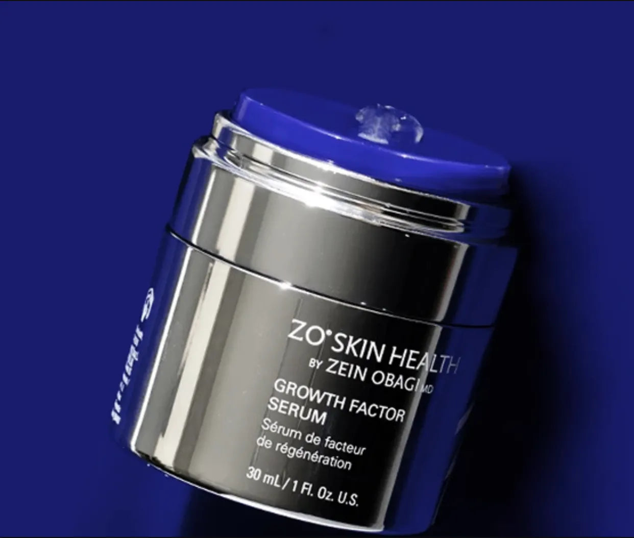 A silver and blue container dispensing a gel-like substance, labeled "ZO® Skin Health by Zein Obagi MD Growth Factor Serum, Sérum de facteur de régénération, 30 mL, 1 Fl. Oz. U.S." against a blue background.