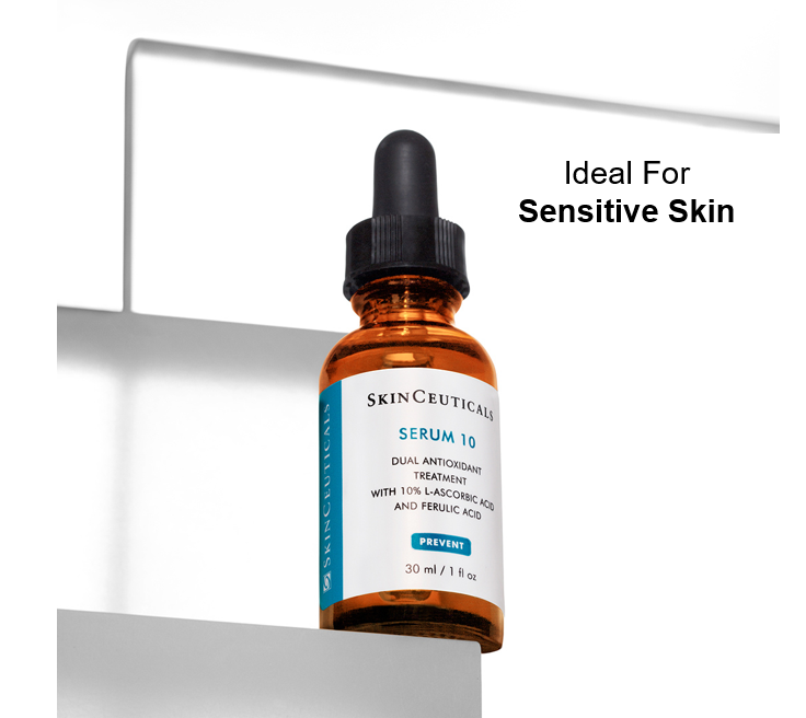 An amber dropper bottle labeled "SkinCeuticals SERUM 10" containing dual antioxidant treatment with 10% L-ascorbic acid and ferulic acid is placed on a mirrored surface. Text reads, "Ideal For Sensitive Skin."