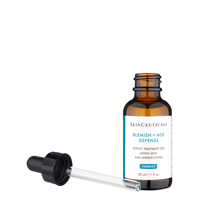 A brown glass bottle labeled "SkinCeuticals Blemish + Age Defense," positioned upright, alongside a dropper with a black cap lying down. Text on the label: "Potent treatment for aging skin and imperfections. 30 ml / 1 fl oz."