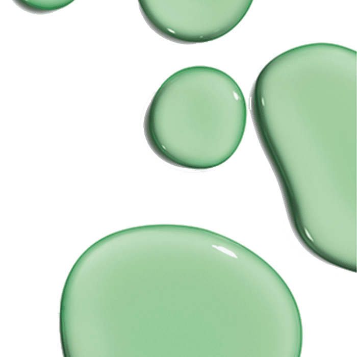 Green liquid droplets of varying sizes sit against a white background, appearing smooth and reflective. The context suggests a close-up view, highlighting their glossy texture.