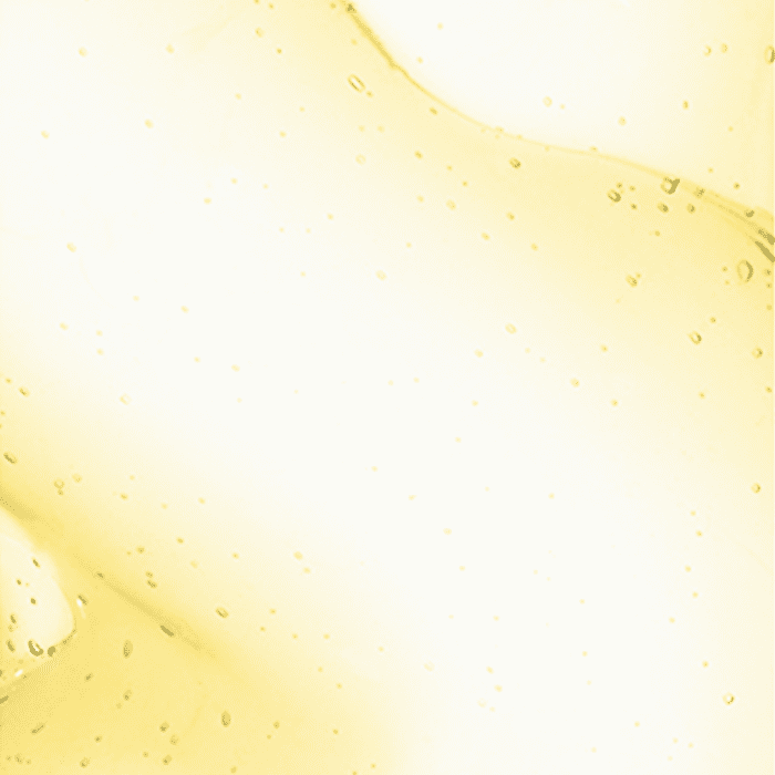 Yellow liquid with numerous small air bubbles suspended throughout it, creating a translucent, slightly textured appearance. Background is uniformly light, emphasizing clarity and fluidity of the liquid.